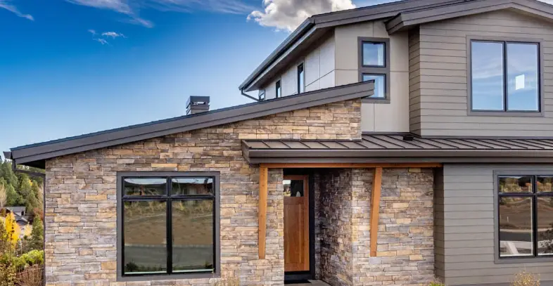 View of well-maintained two-story home in the middle of the day within a peaceful neighboord with many surrounding trees.